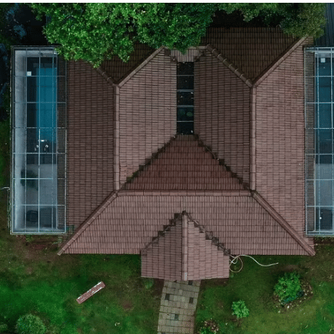 An aerial view of a building with a unique M-shaped roof, surrounded by lush greenery at Abad Brookside Lakkidi, Wayanad.