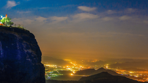 a panoramic view from a hill under vibrant sky showcasing the lit city