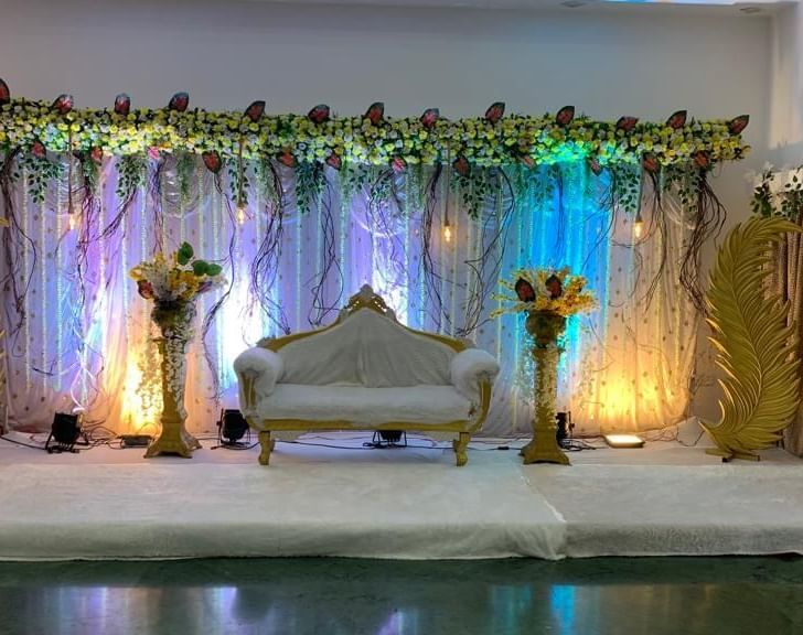 Floral stage setup with soft lighting and golden curtains, ideal for weddings and special events at Mayur Retreat.