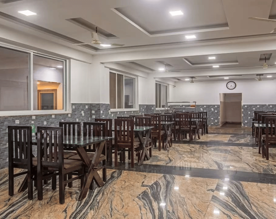 Indoor dining area with polished flooring and neatly arranged wooden tables and chairs at Siri Ambari Resorts and Spa.
