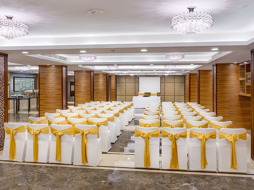 A view from behind of Regency 1 Hall, one of the best Banquet Halls in Park Street, with theatre style seating, a stage at the far end and many chandeliers on the ceiling at Kenilworth Hotel, Kolkata.