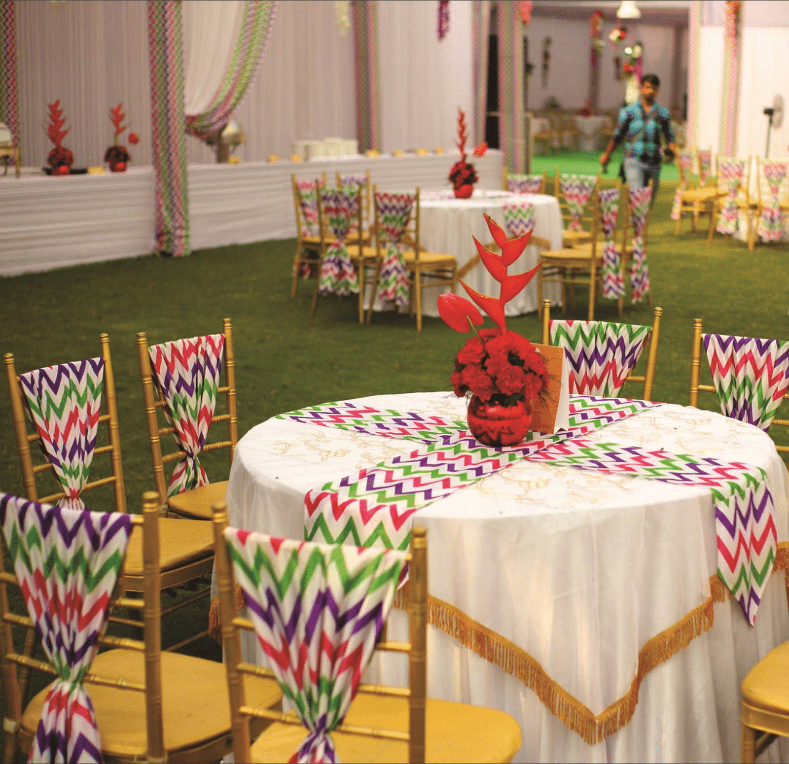 Chairs around a table with colourful printed covers and floral centrepieces | Gemini Continental