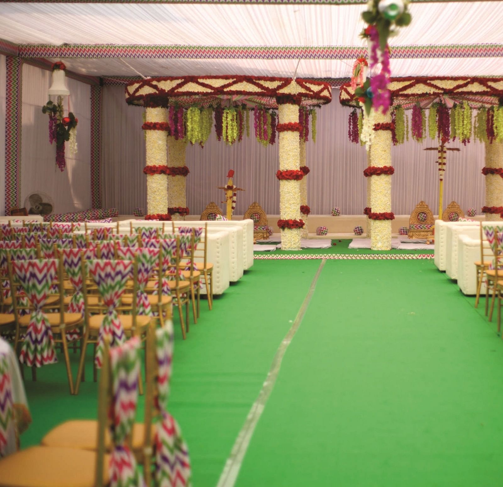 Stage setup for a wedding in a decorated banquet space with a central aisle and chairs on either side | Gemini Continental