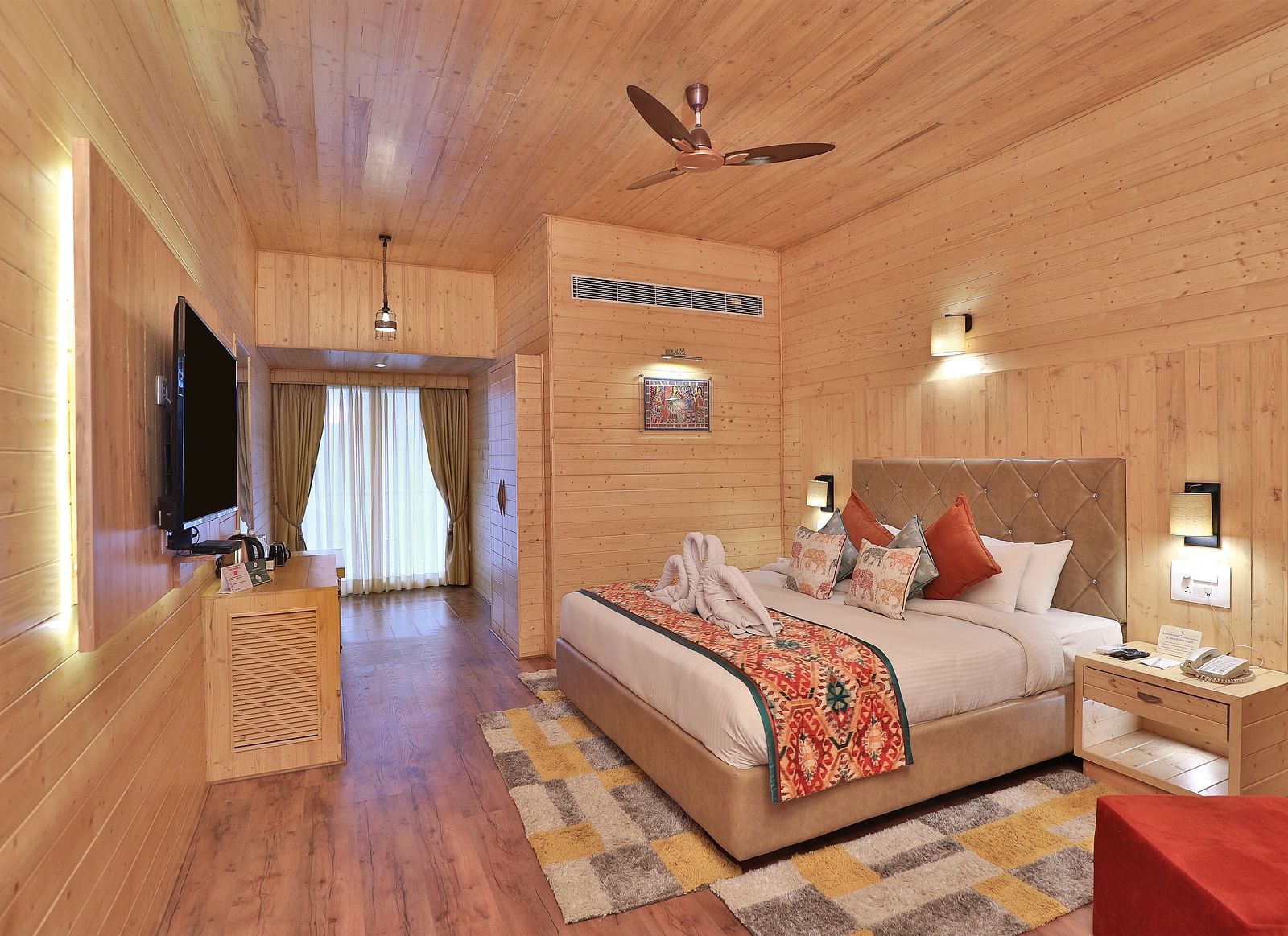 A cosy bedroom with a plush bed with colourful accents, and warm lighting. - Bamboo Saa Resort & Spa, Udaipur