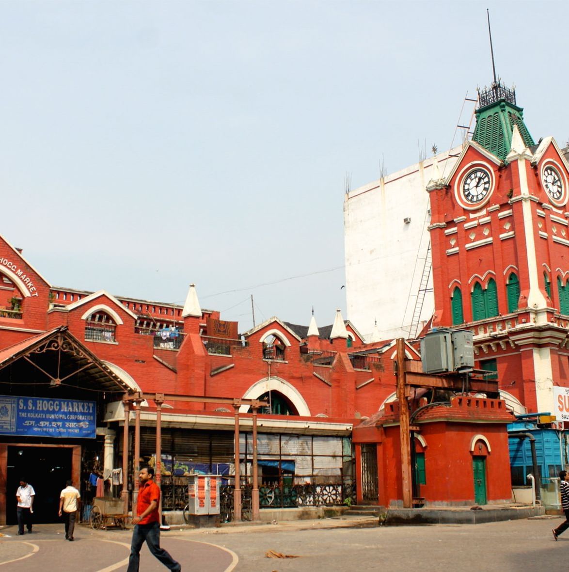 Red brick building with clock tower and people walking outside.