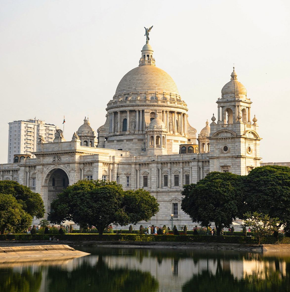 Victoria Memorial building with domes, surrounded by trees and water.