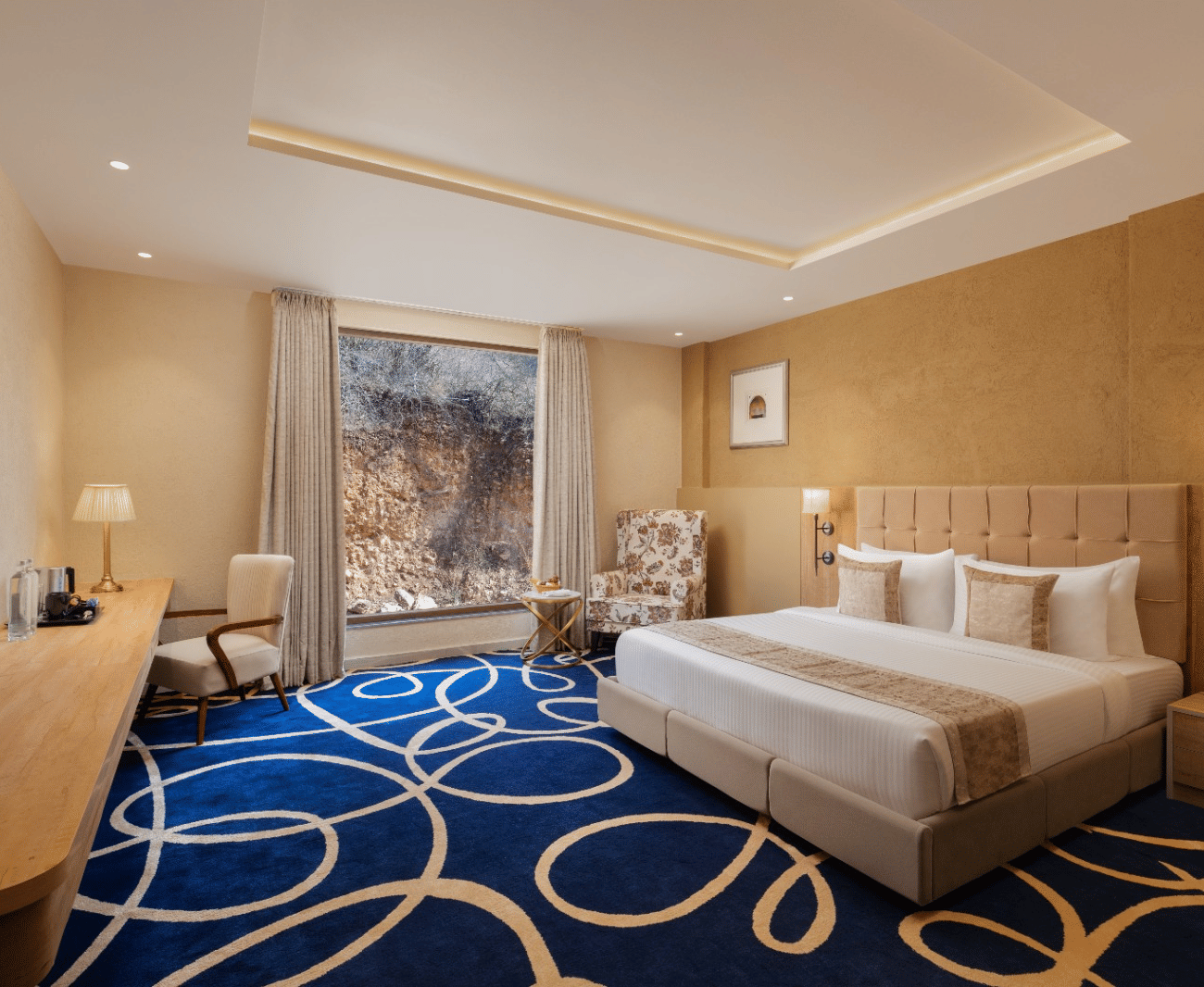 Superior room with king bed and blue accent rug at Essentia Luxury Resort & Spa, Udaipur.