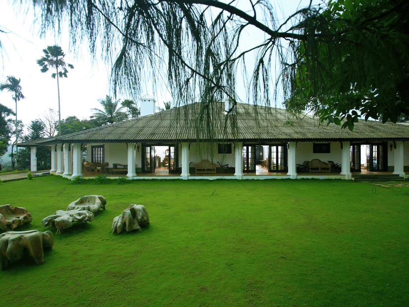 green lawn with a bungalow in the background at Parisons Plantation - one of the best Farm Houses in Wayanad