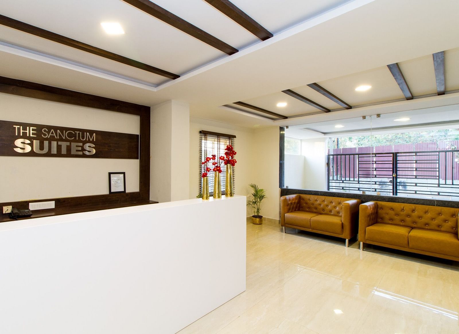 A hotel reception area featuring a white desk and two sofas at Sanctum Suites Whitefield, Bangalore.