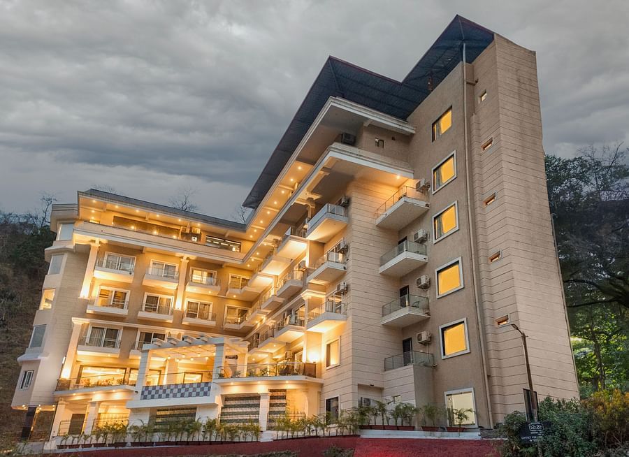 Facade of Stone Wood Hotel, Rishikesh with a cloudy sky in the background.