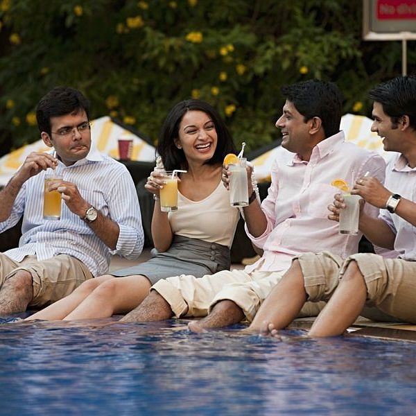 a group of people relaxing by the pool with drinks in their hands