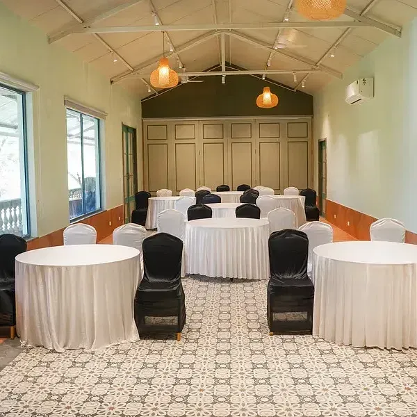 A conference hall set up with chairs around tables at Indie Stays Resort, Goa.