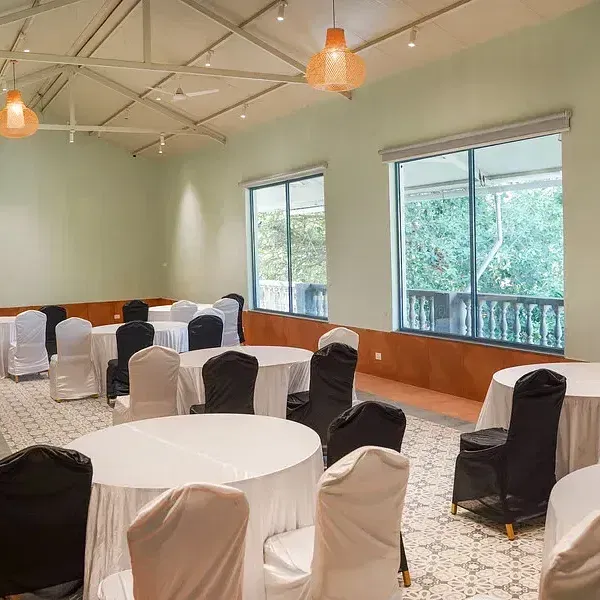 A conference hall set up with chairs around tables at Indie Stays Resort, Goa.