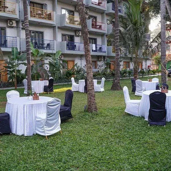 An open-air banquet space in the lawn with comfortable chairs around tables at Indie Stays Resort, Goa.