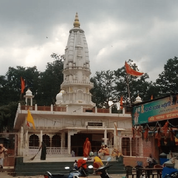 Bhartrihari Temple with a tall tower stands against a cloudy sky.