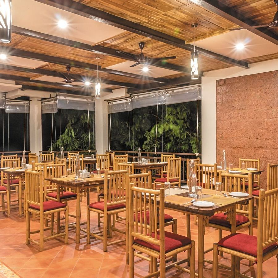 The spacious indoor dining area at Forest Escapes Koyna offers ample seating under bright lighting.