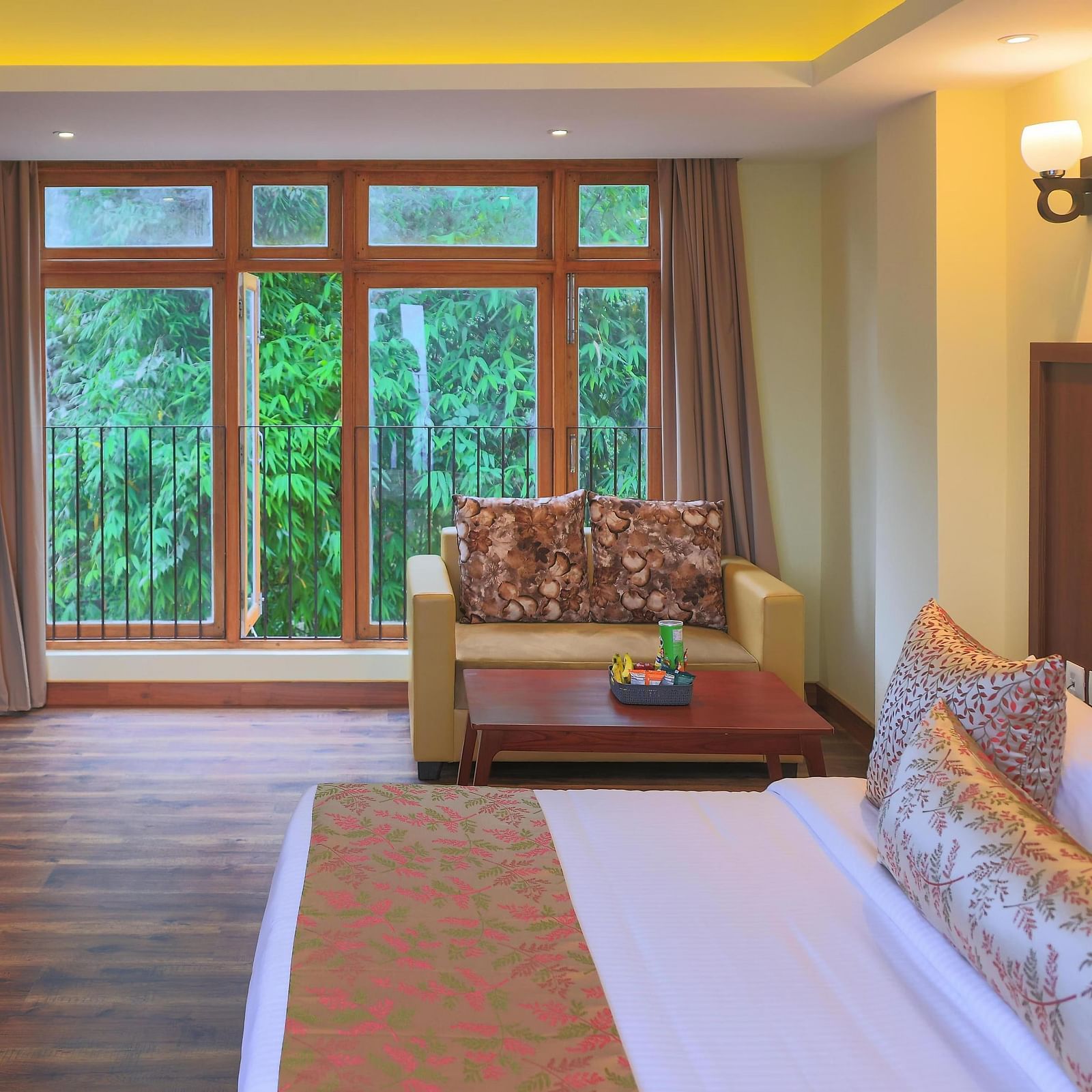 a spacious Premier Plus room at Yashshree Karbari Resort & Spa, Yangang featuring huge windows with lush greenery outside
