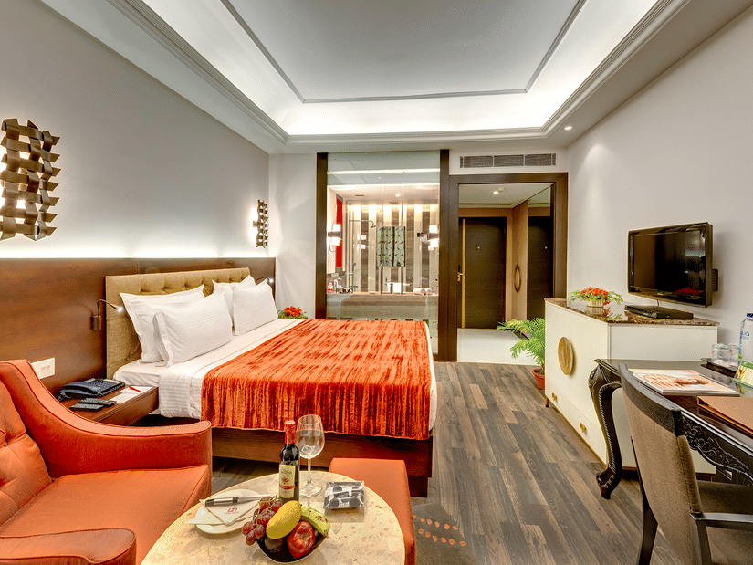 A modern hotel room with a plush king size bed, a comfortable seating area and warm toned decor, perfect for a relaxing stay – Hotel Hindusthan International, Kolkata