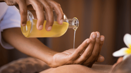 A technician pouring massage oil to its client.