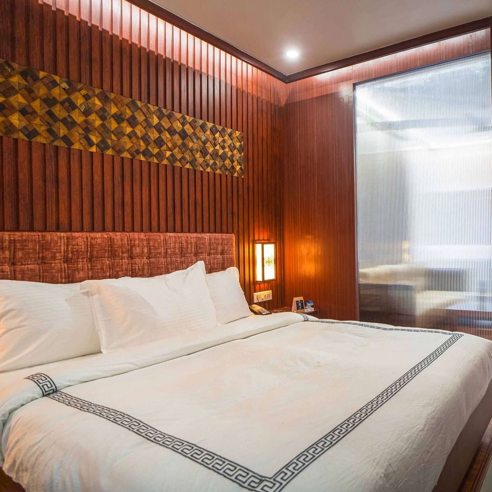 A stylish bedroom at Mansha Palace features a comfortable bed and a partial view into an adjacent area with a desk.