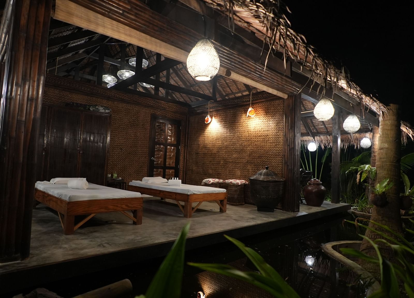 Open-air spa setup with side tables and hanging lights at Flower Island Resort.