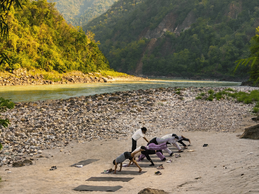 A group of people indulging into an early morning yoga session by the Ganges, with a beautiful backdrop of the hills.