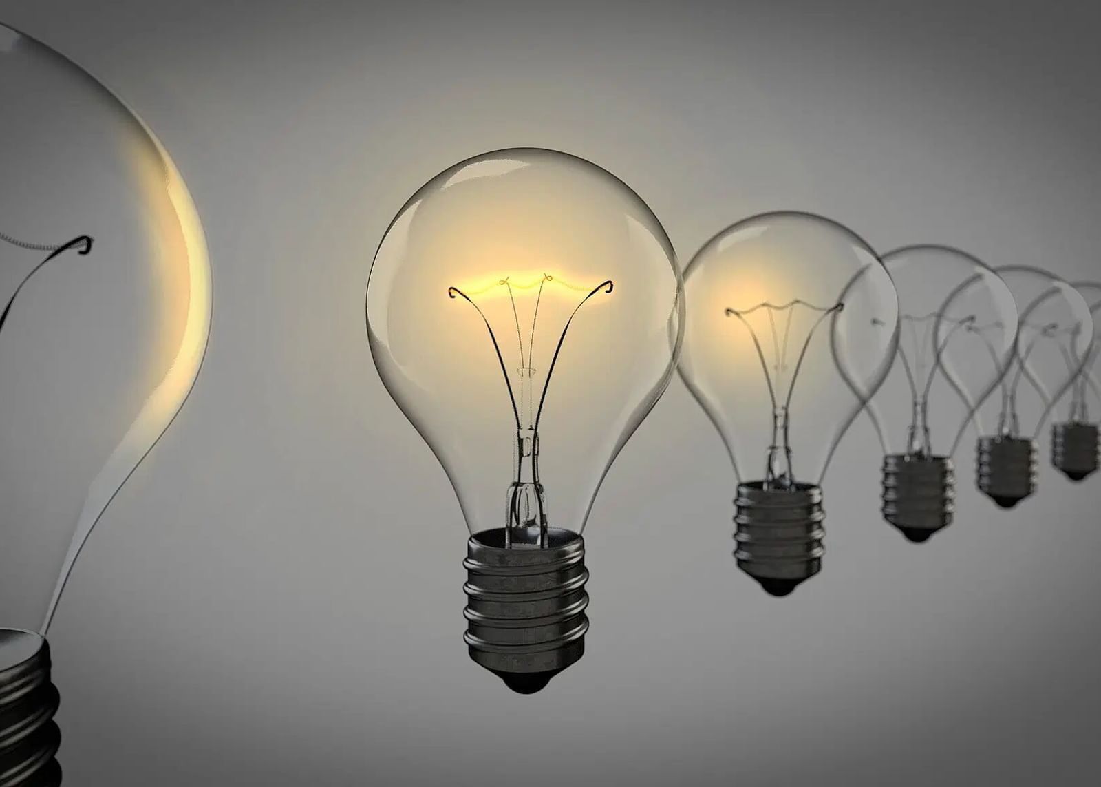 A row of illuminated light bulbs, with the first bulb appearing larger and brighter.