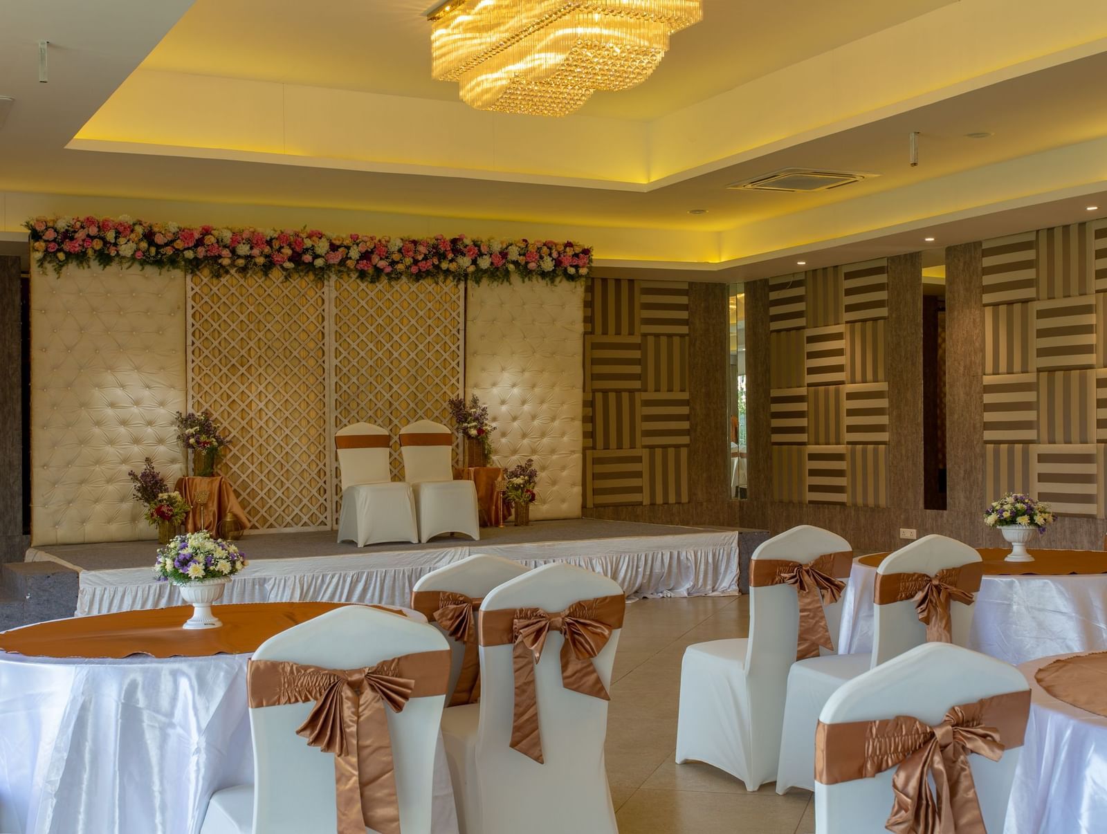 A brightly lit indoor banquet hall or reception area with tables and chairs set up, featuring elegant decor and a patterned wall | Grande Pavillion | Grand Bay Resort and Spa