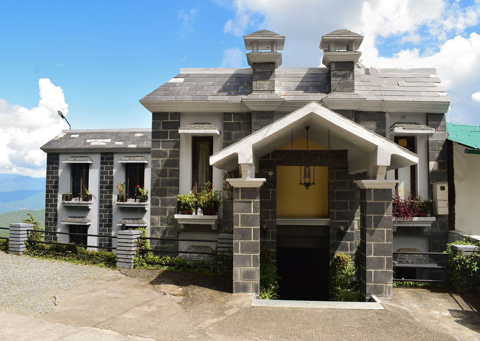 Traditional stone building with a wooden door and a balcony overlooking the mountains.
