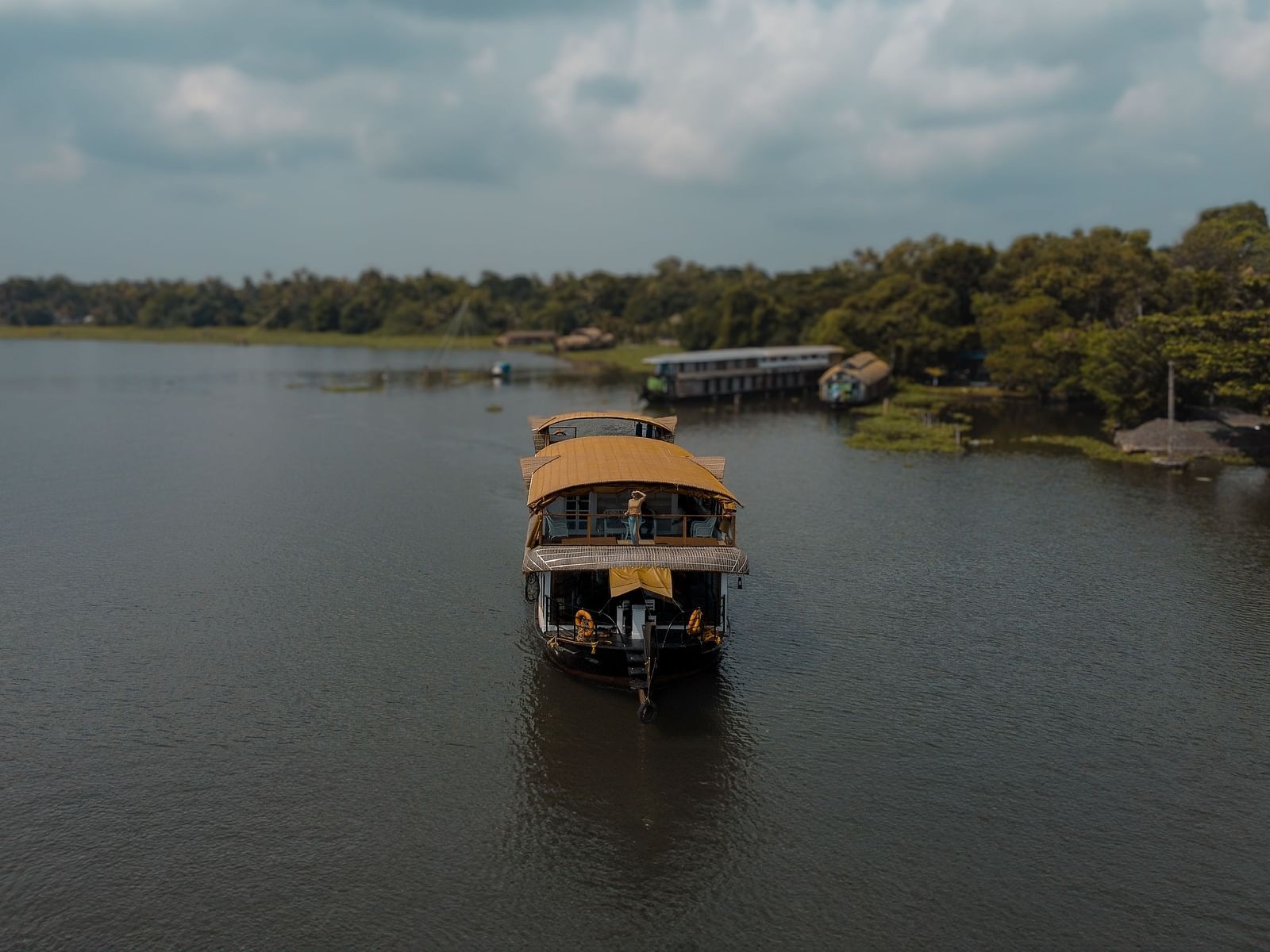 A cruise sailing across the Vembanad Lake with lush greenery in the background - BluSalzz Villas - Muhamma Resort, Alleppey