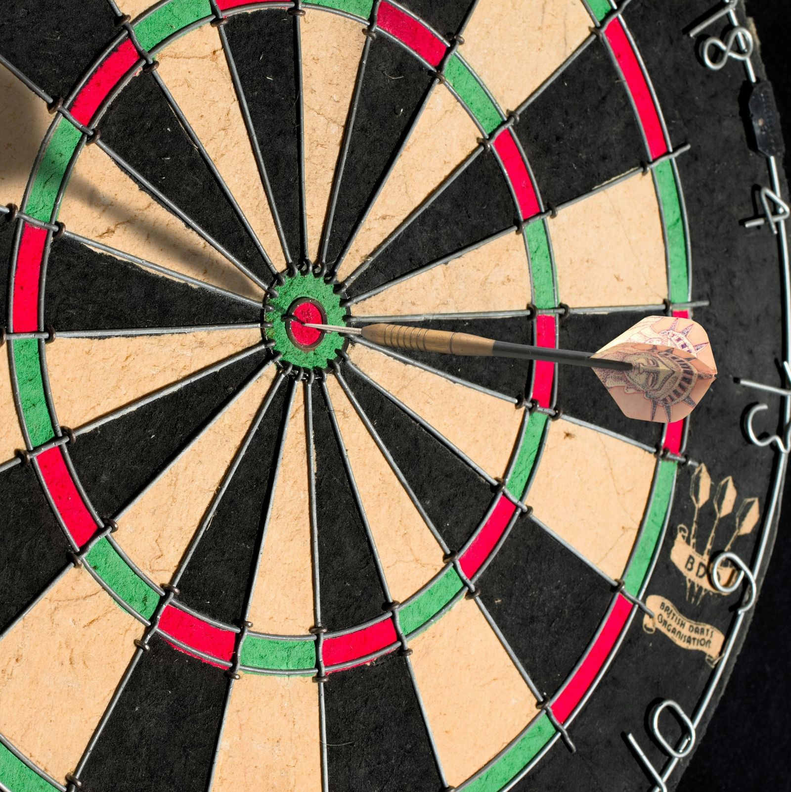A dart board with a dart placed at its bull's eye.