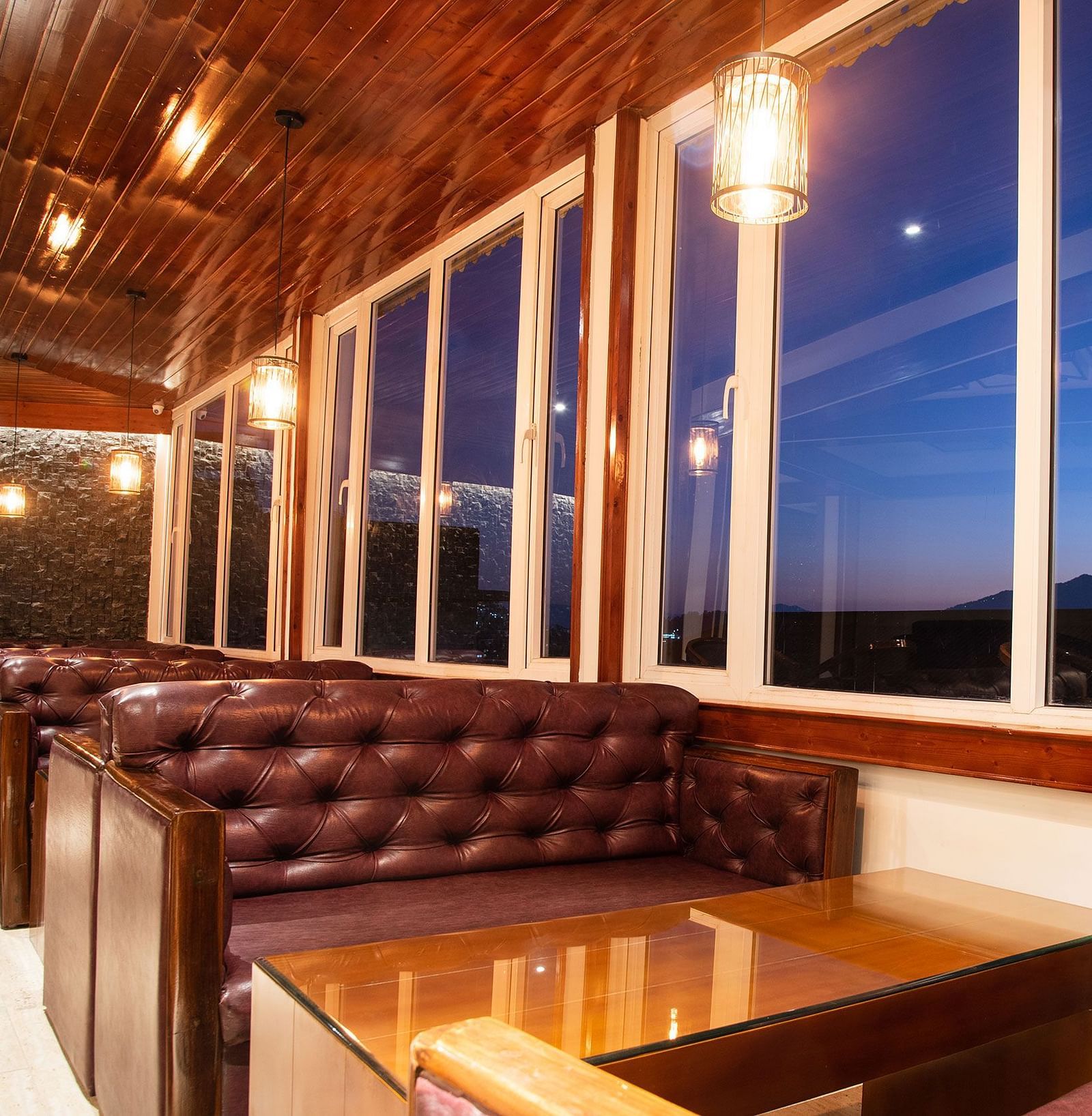 A seating arrangement of a bar in gangtok with leather couches and a well furnished table - Summit North Star, Gangtok