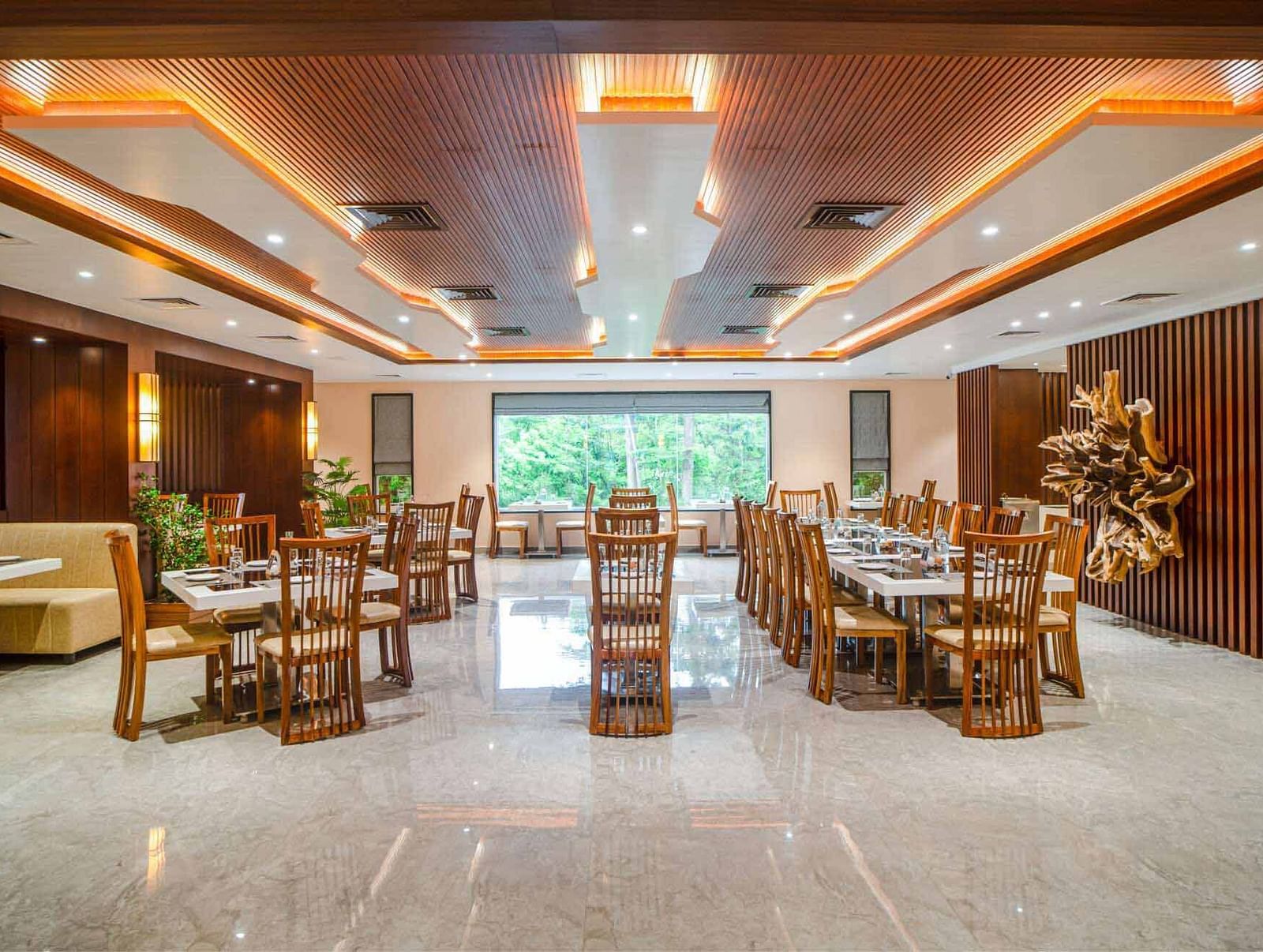 The well-lit dining area at Mansha Palace in Port Blair features neatly set tables and comfortable wooden chairs.