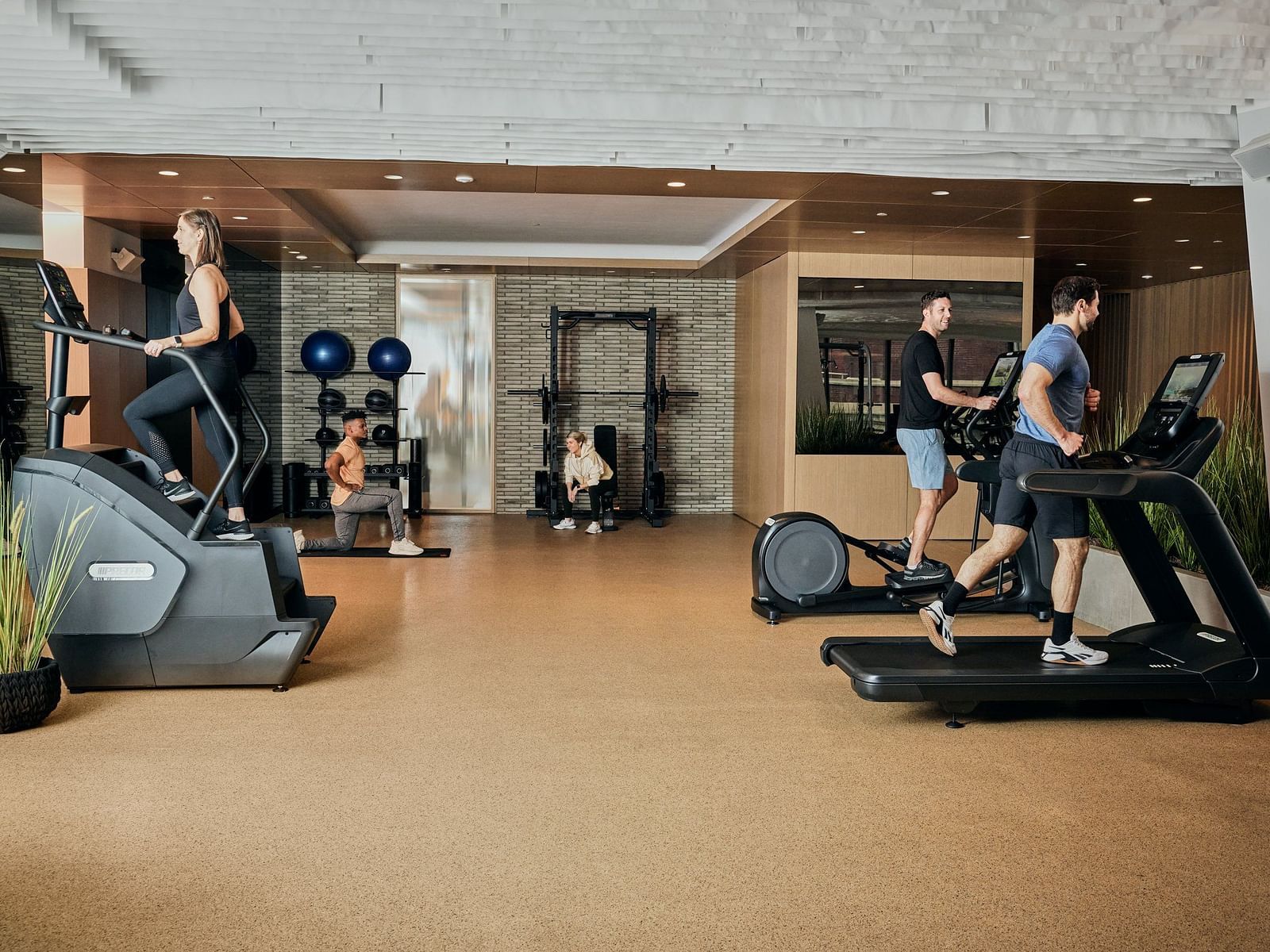 A fitness centre with treadmill and other gym equipment's and  surrounded by  people.