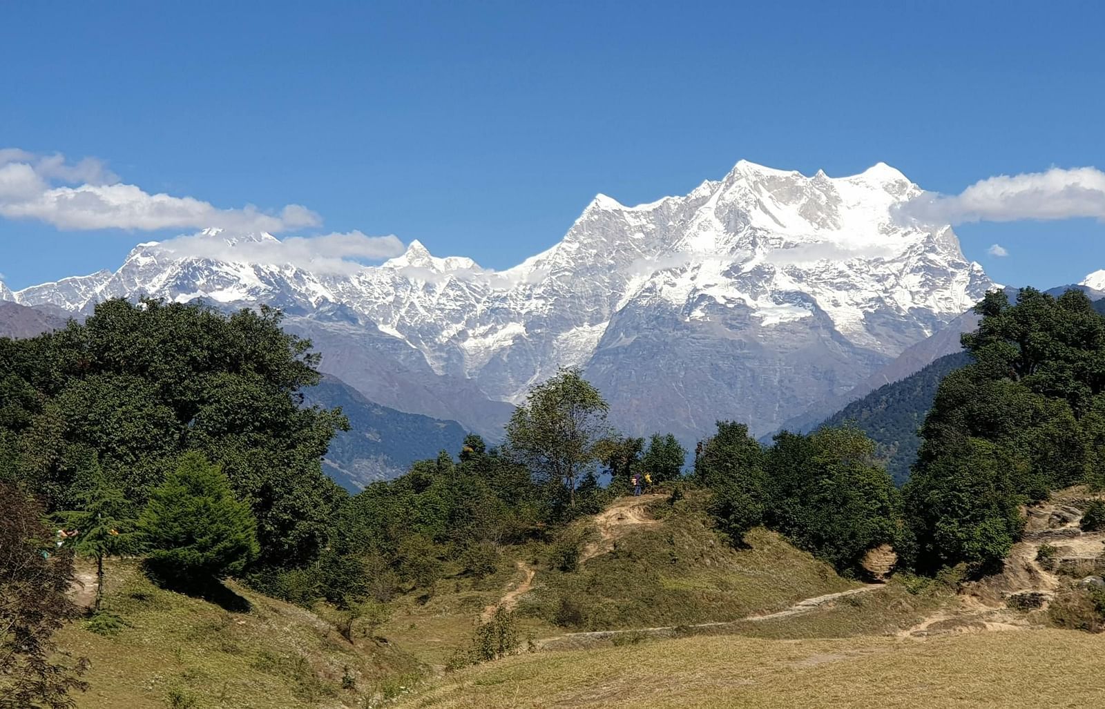 Majestic mountain range with snow-capped peaks, towering over a lush green valley.