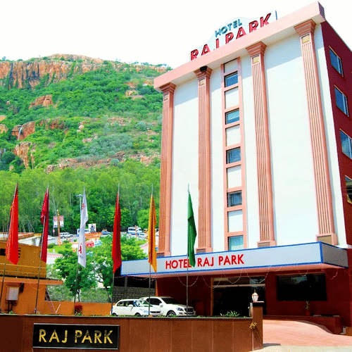 Facade of Raj Park Hotel, Tirupati, with a green mountain in the background.