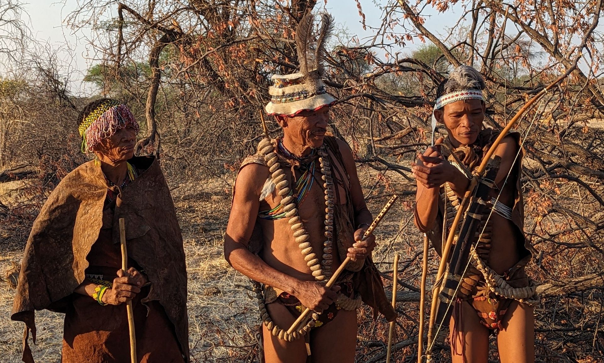 San people in traditional attire with hunting tools.