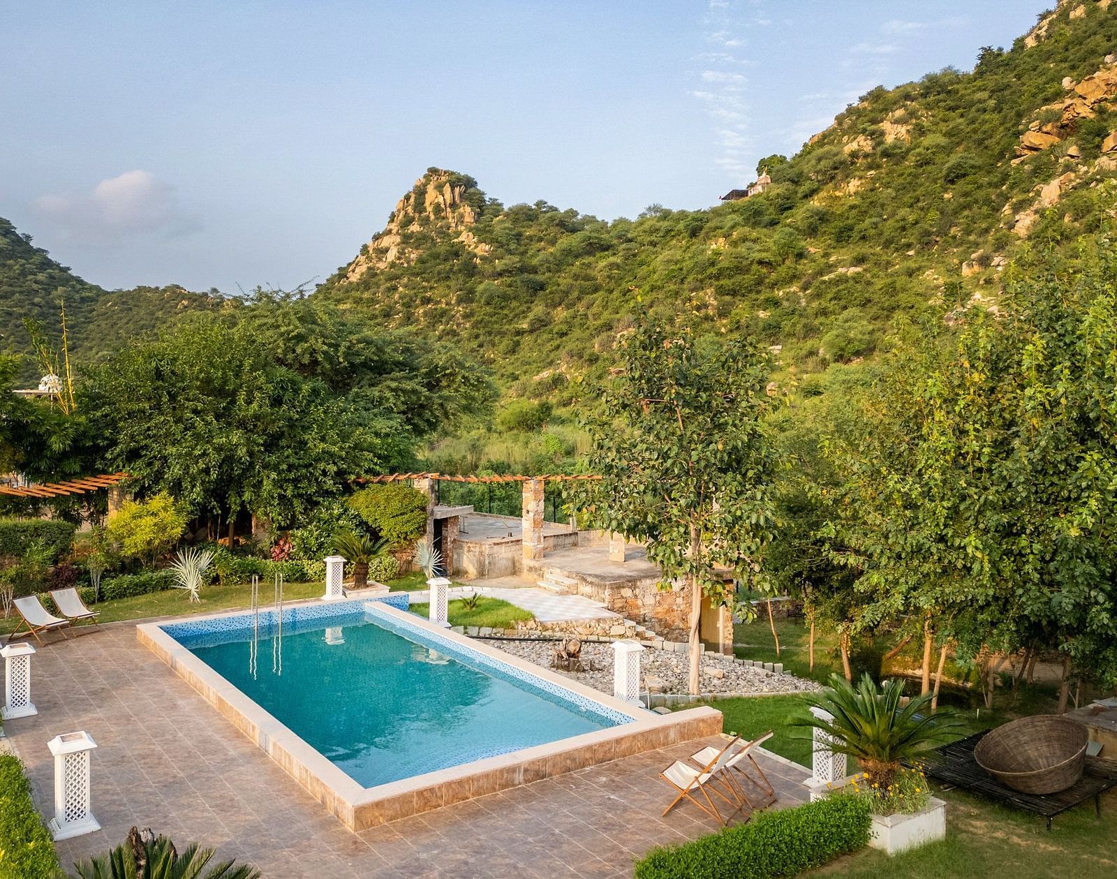 An outdoor swimming pool surrounded by lush greenery at Valley by Grassfield.