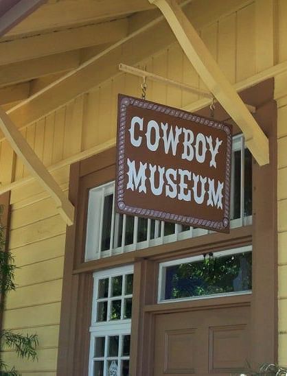 A sign reading Cowboy Museum hung outside a window - The Groveland Hotel.