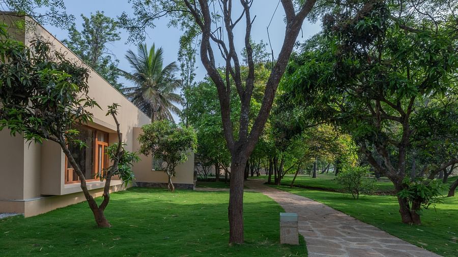 Garden path with trees and grass, building in background, outdoor landscape, natural setting - Shreyas Retreat