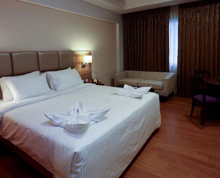 Side view of room with bed, sofa and table with chair at Fressotel Seetharam, Coimbatore