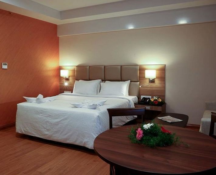 Room with bed and a table with flowers on top at Fressotel Seetharam, Coimbatore