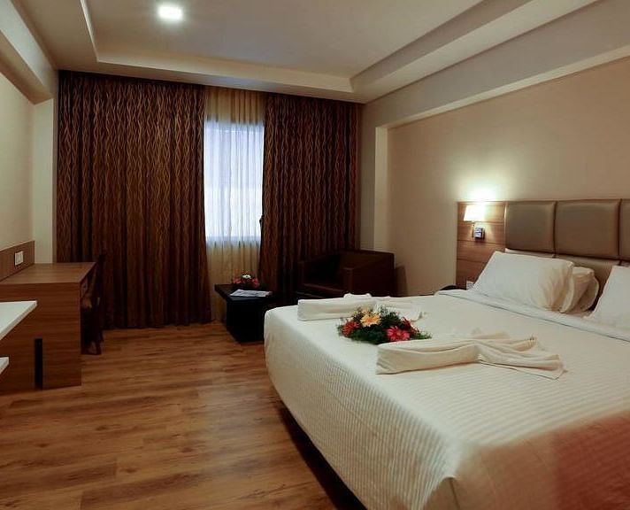 Spacious room with television, bed and table at Fressotel Seetharam, Coimbatore