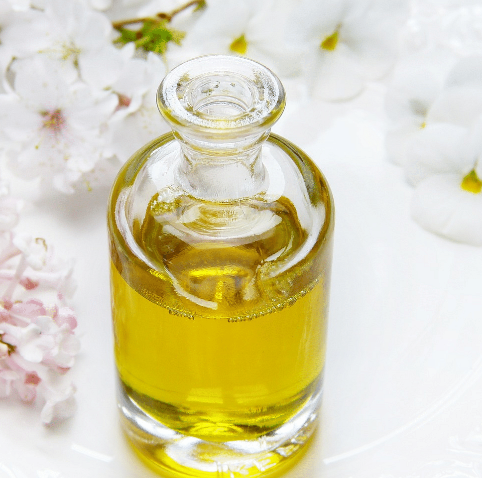 A glass vessel filled with essential oil nestled on a delicate floral bed .