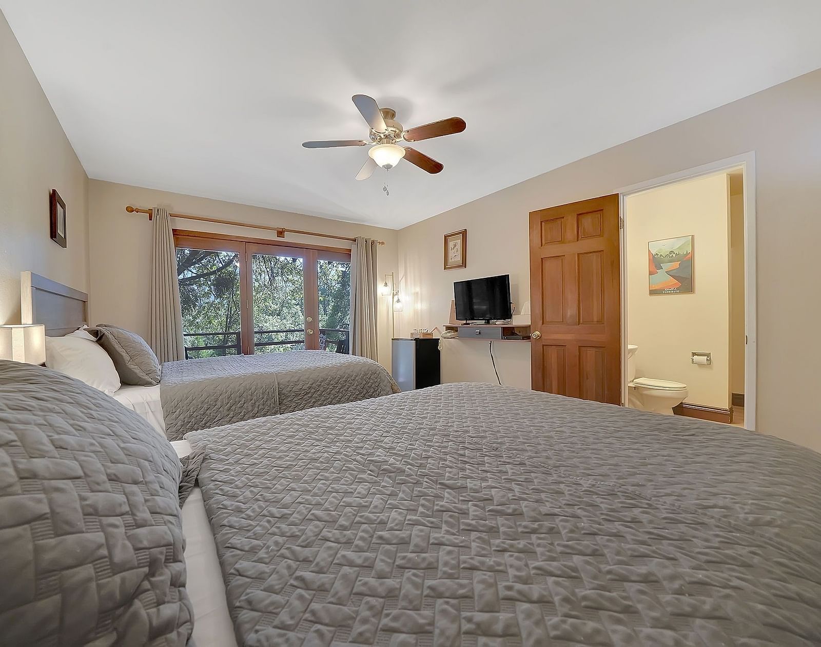 A view of a room at Narrow Gauge Inn with twin beds and a television.