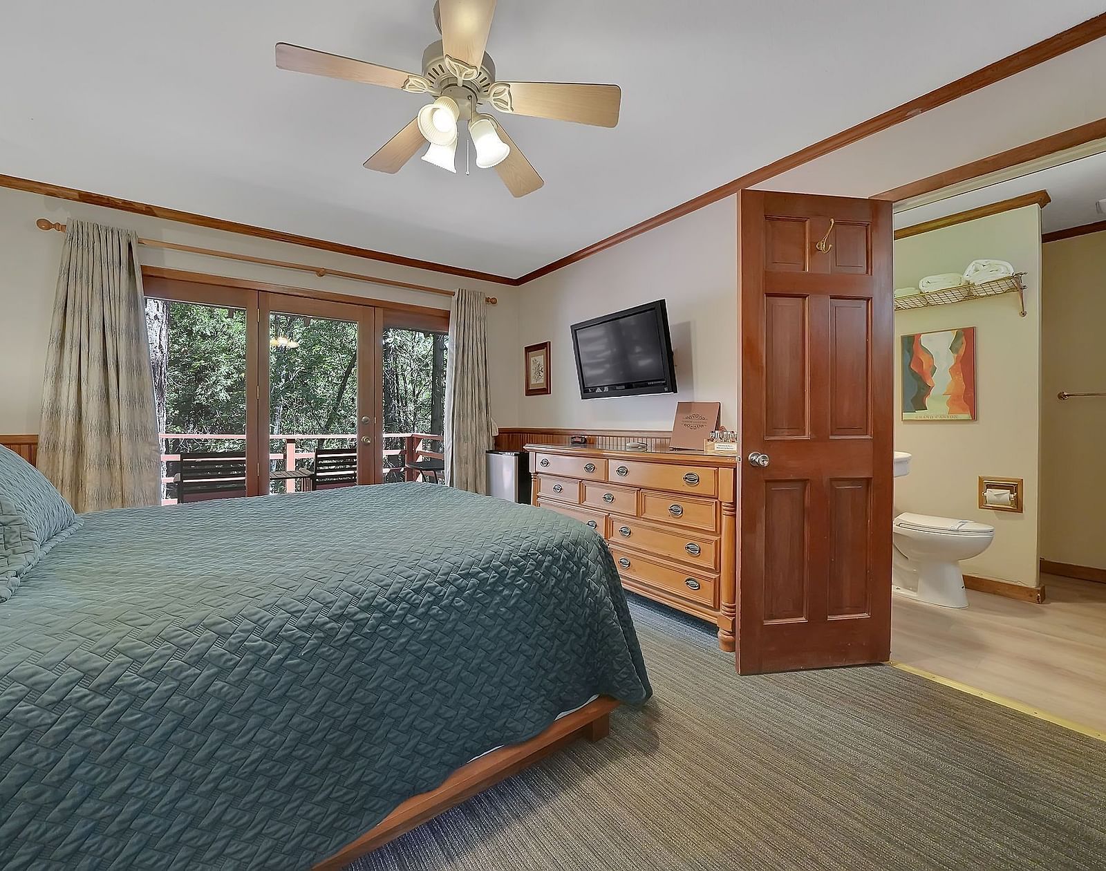 A view of a room at Narrow Gauge Inn with a double bed and sliding doors opening to a balcony.