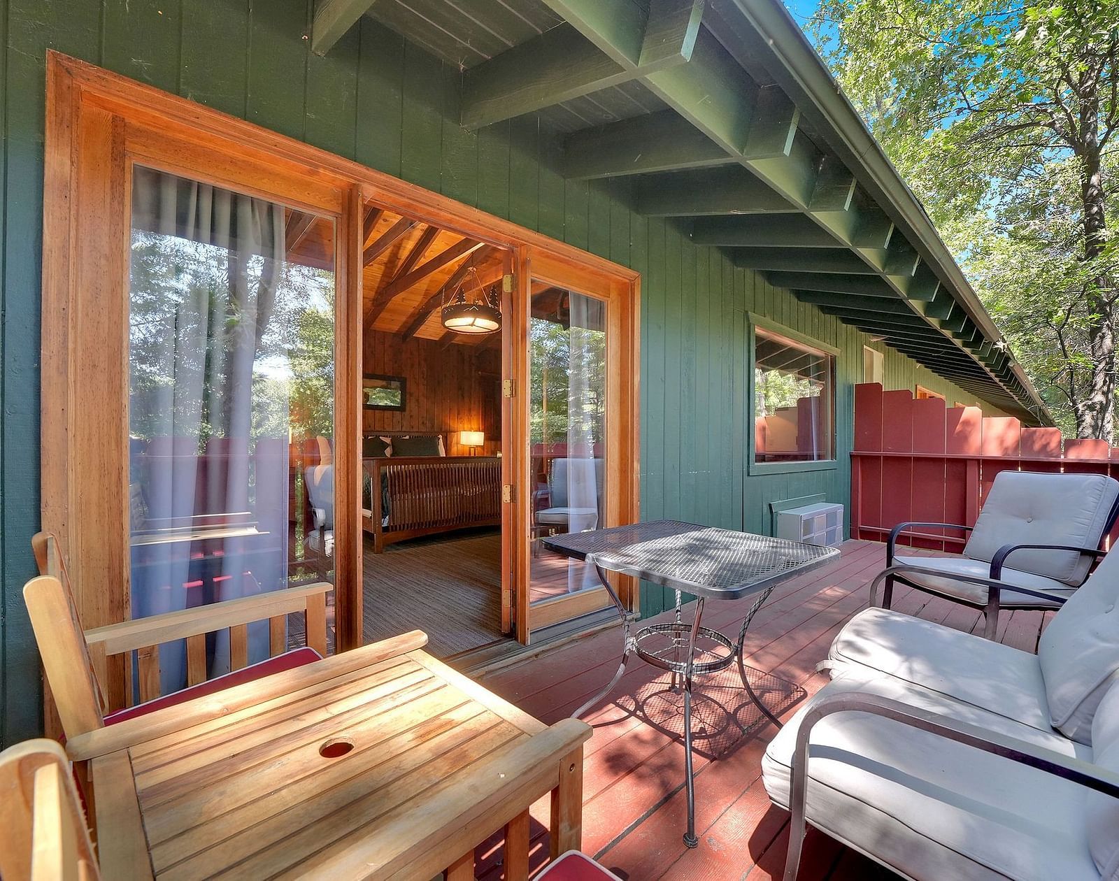 A view of the outdoor patio area o a cabin with sofa seating and a coffee table - Narrow Gauge Inn - A Serenite Hotel Near Fish Camp.