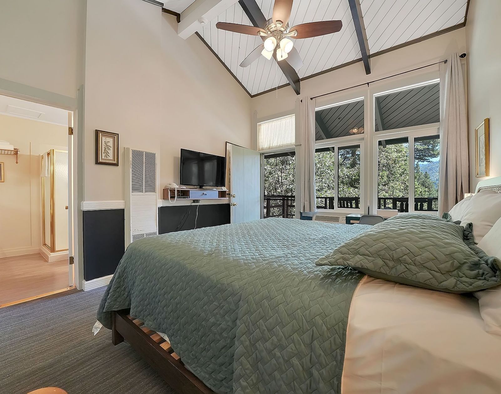 A view of a room at Narrow Gauge Inn with a double bed and sliding doors opening to a balcony.