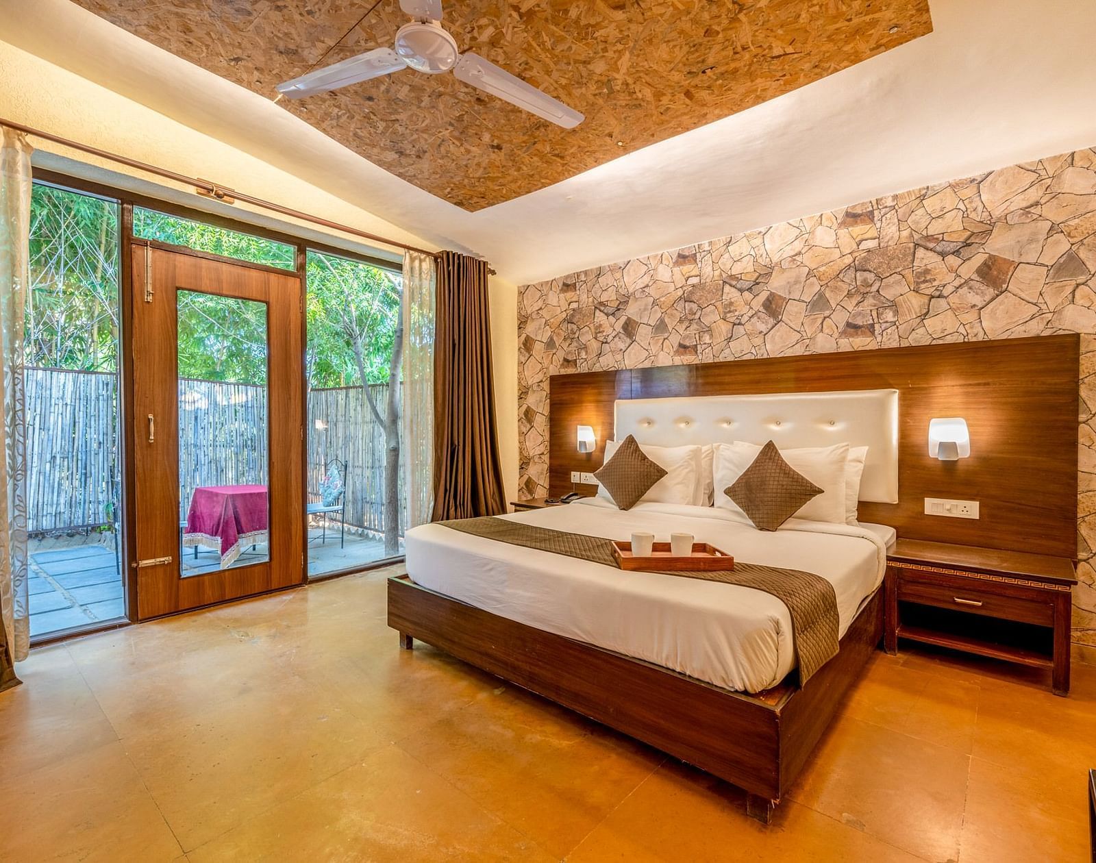 A room featuring a bed with a wooden headboard and glass doors on the side at Valley by Grassfield. 