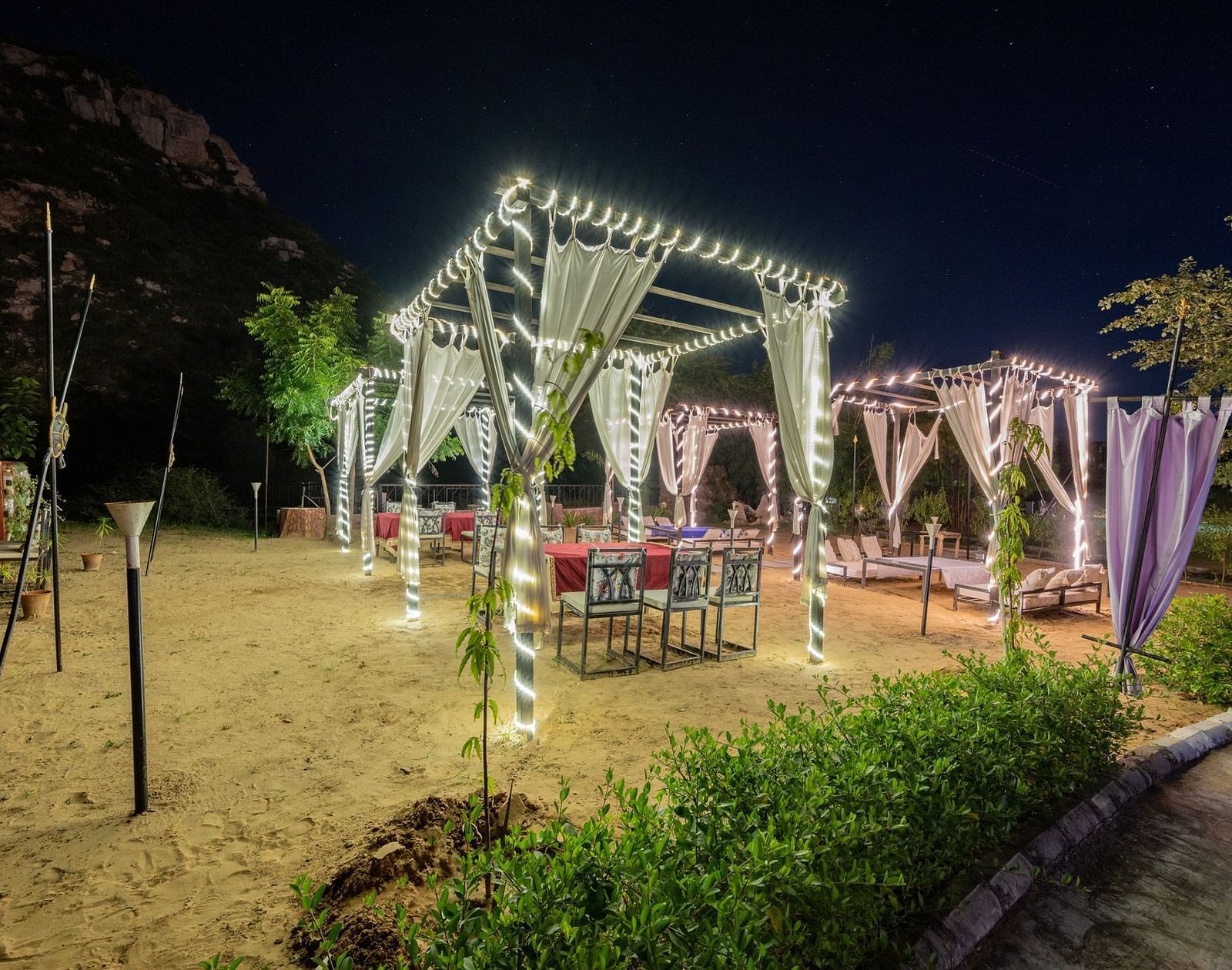 Night view of an open dining space decorated with sheer curtains and lights at Valley by Grassfield.